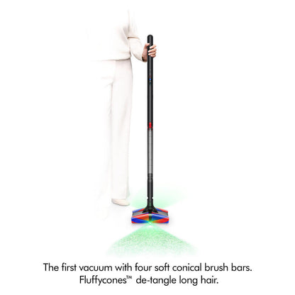 A person in white clothing holds a cordless stick vacuum cleaner with four soft conical brush bars at the base, shown against a white background with green and red light effects and product text below.