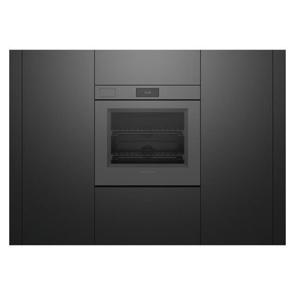 A built-in wall oven with a dark gray metallic finish, featuring a glass door, interior racks, and a small digital display above the door, set within matching dark gray cabinetry.