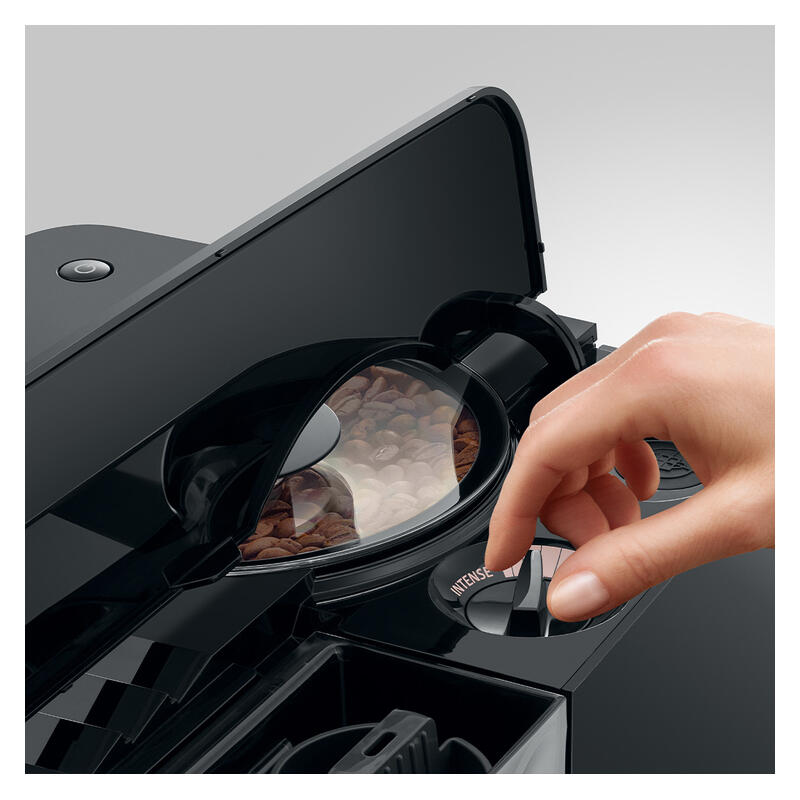 Close-up of a black coffee machine with its bean hopper lid open, showing coffee beans inside, and a human hand pressing a button on the front.