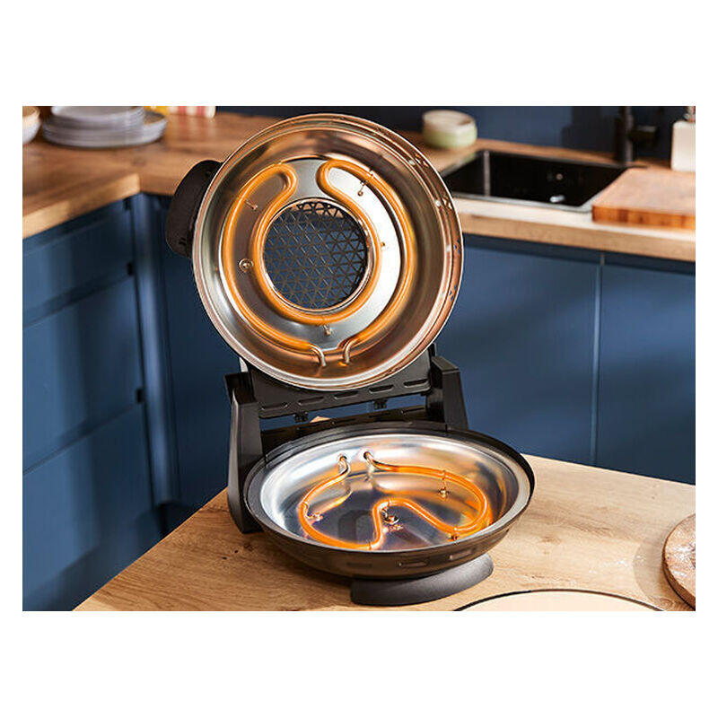 A countertop electric waffle maker with the lid open, showing glowing orange heating elements inside, set on a wooden kitchen counter with blue cabinets in the background.
