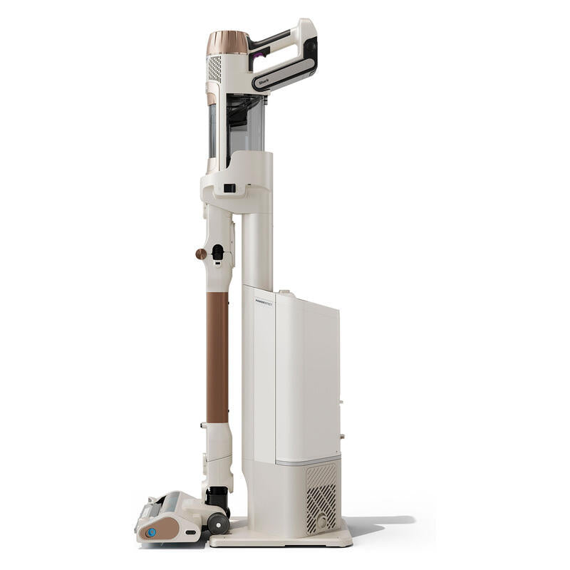A tall cordless stick vacuum cleaner in a warm off-white and brown color scheme, shown standing upright on its charging base against a clean white background.