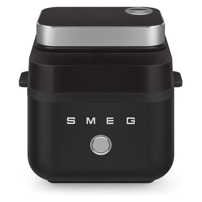 A black SMEG countertop air fryer with a brushed silver top band, silver side handles, and a silver front button, shown on a white background.