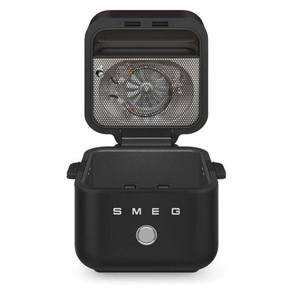 A black SMEG countertop air fryer with its lid open, showing the interior fan and mesh filter, on a clean white background.