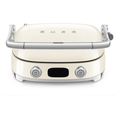 Cream-colored SMEG electric grill with a glossy finish, featuring a silver metal handle, two silver control buttons on the front, and the SMEG logo on the lid.