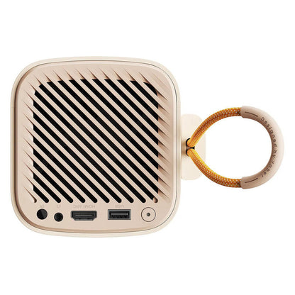 A square portable projector in a warm beige/cream color with a black diagonal grille pattern, featuring a braided yellow-orange carrying strap attached on the right side.