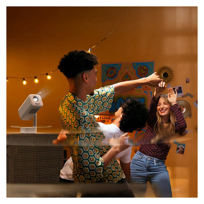 A group of three young people dancing and laughing in a warmly lit indoor space with string lights, a projector on a stand, and colorful wall art. The central person wears a green and yellow geometric patterned shirt, and the scene has a stylized motion-blur overlay.